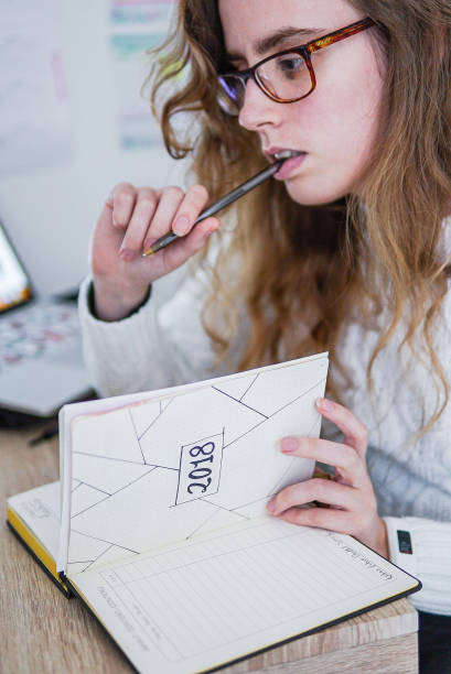 A girl working at her desk. A girl working at her desk with a bullet journal and her computer. bullet journal photos stock pictures, royalty-free photos & images