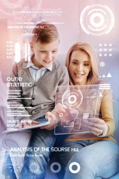 istock Emotional programmer holding a transparent gadget and her curious child looking 968841224