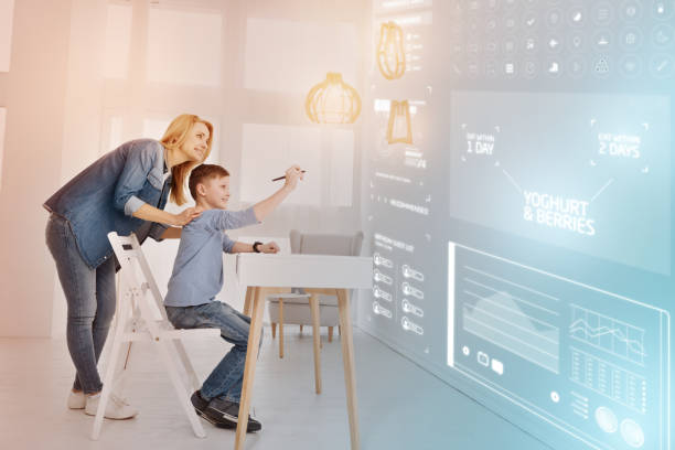 istock Smiling boy holding a stylus and his mother looking at him 968841594