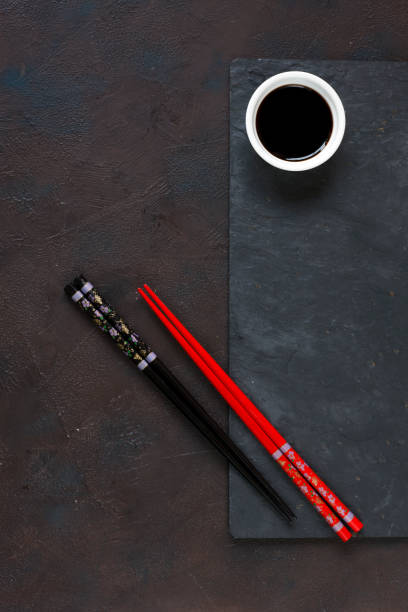 istock Chopsticks and bowl with soy sauce on black stone background 968841766