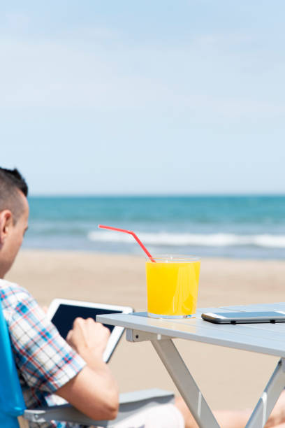 homme avec tablette sur la plage - reading beach e reader men photos et images de collection