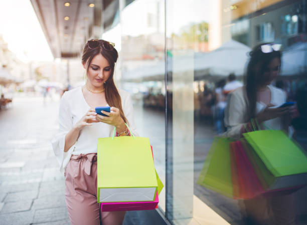 istock Young woman with shopping bags using smartphone. 968845880