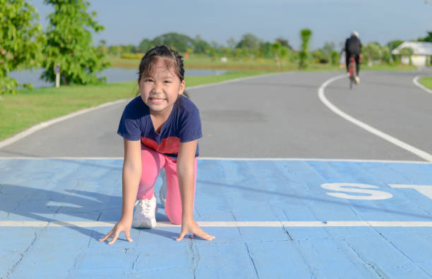トラック上で実行する準備ができている位置に笑顔の女の子 - starting line competition running jogging ストックフォトと画像