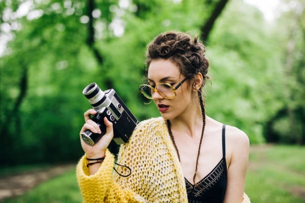 istock Young woman using an vintage cinema camera in a park 968846374