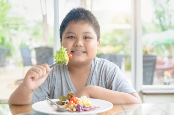 Obese fat boy enjoy to eat vegatables salad. Obese fat boy enjoy to eat vegatables salad, diet and Healthy food concept overweight child stock pictures, royalty-free photos & images