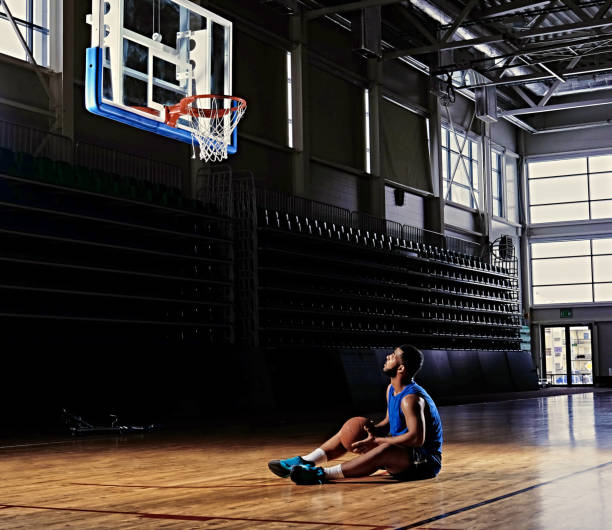 istock Basketball player sits on a field under the hoop. 968849146