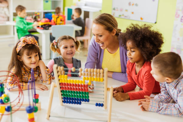 istock Happy teacher and kids learning to count on abacus at preschool. 968852086