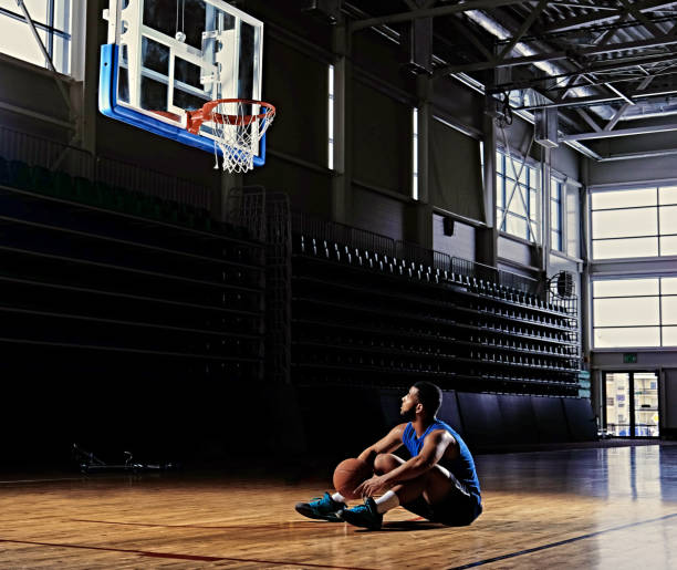 istock Basketball player sits on a field under the hoop. 968853372