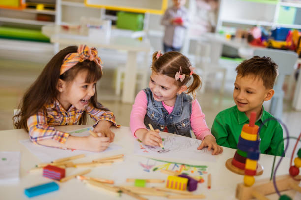 istock Happy kids talking while drawing in preschool. 968853434