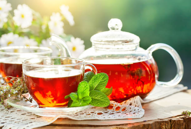 istock Cup with hot tea with mint and a thyme on a wooden table in a summer garden 968855962