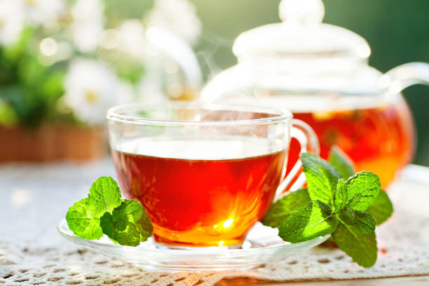 istock Cup with hot tea with mint and a thyme on a wooden table in a summer garden. Selective focus 968856132