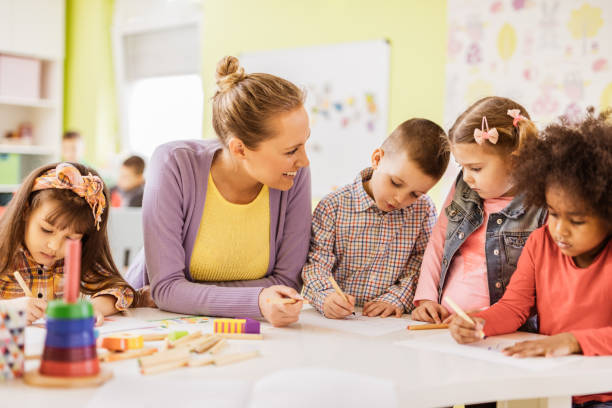 istock Happy teacher having an art class with small kids in kindergarten. 968856636