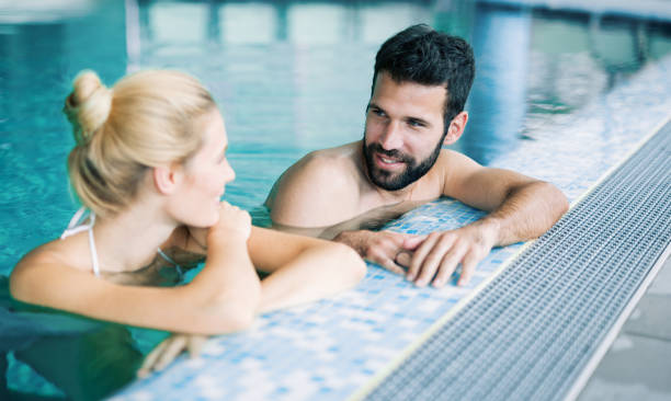 istock Happy attractive couple relaxing in swimming pool 968856780