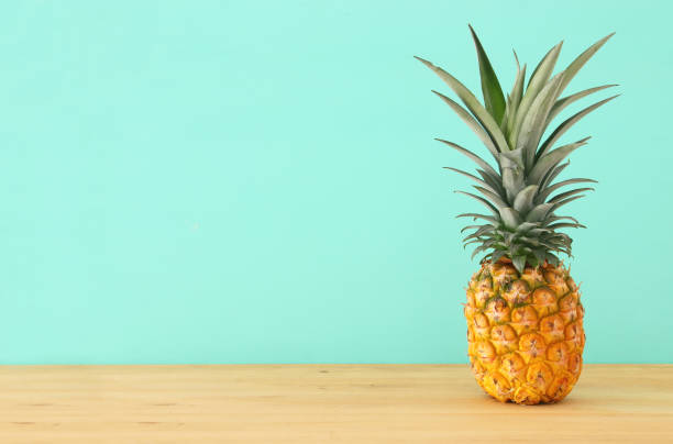 istock Pineapple on wooden table. Beach and tropical theme. 968856974