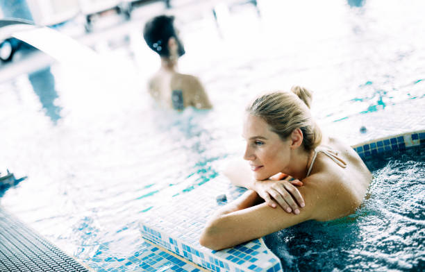 portrait de femme belle relaxante dans la piscine - health spa swimming pool relaxation indoors photos et images de collection