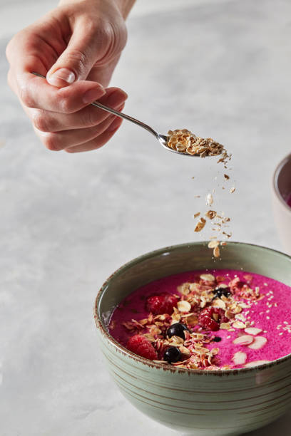 istock A female hand prepares a useful smoothie with berries and granola 968857074