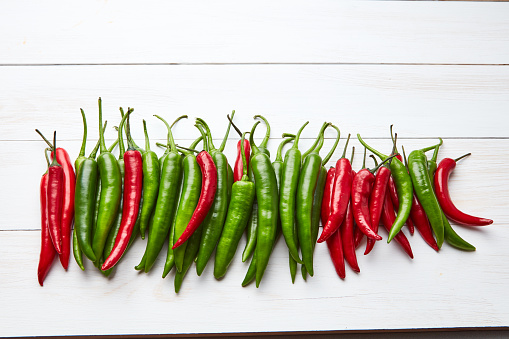 Mexican hot chili peppers green and red on white wooden background, flat lay