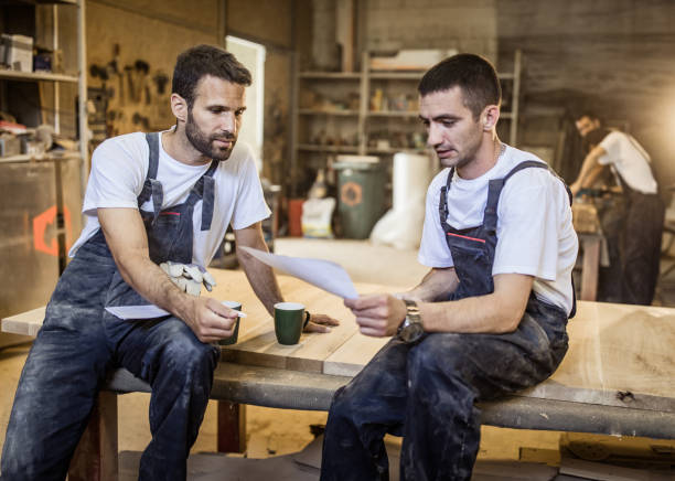 istock Young carpenters going through plans on a coffee break in a workshop. 968878398
