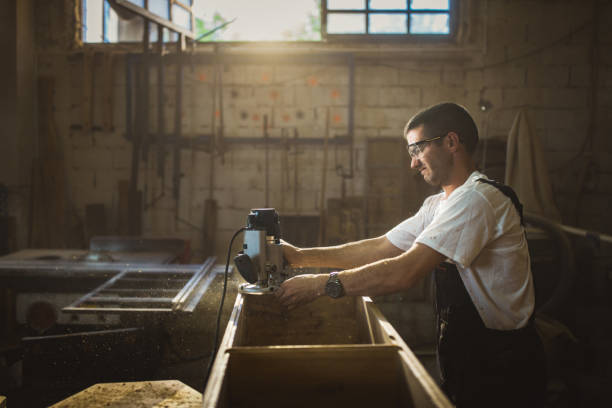 istock Young manual worker working with plane on a piece of wood in workshop. 968878930