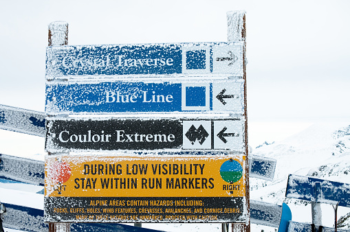 Snow covered ski trails signs Blackcomb/Whistler Mountains, BC.  Intermediate (blue square) and expert (black double diamond) markers.