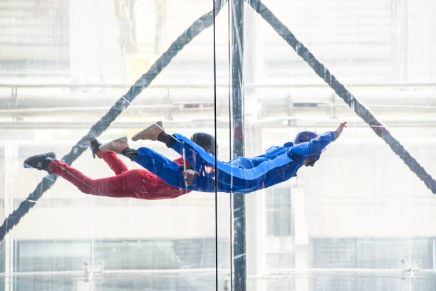 Skydivers in indoor wind tunnel, free fall simulator Skydivers in indoor wind tunnel, free fall simulator skydiving stock pictures, royalty-free photos & images