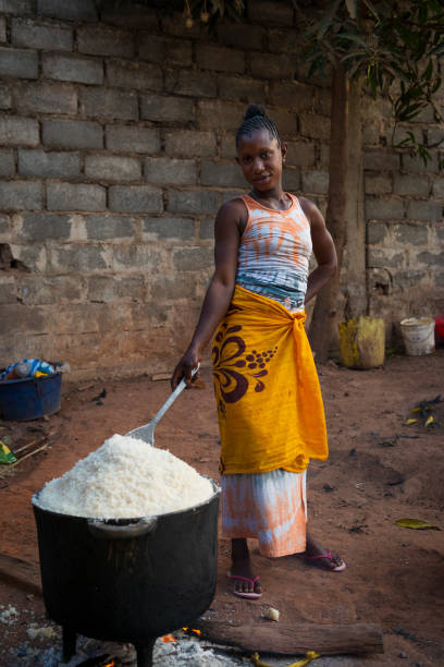 młoda kobieta gotująca ryż na starej patelni, w dzielnicy cupelon de cima w mieście bissau - africa african descent cooking african culture zdjęcia i obrazy z banku zdjęć