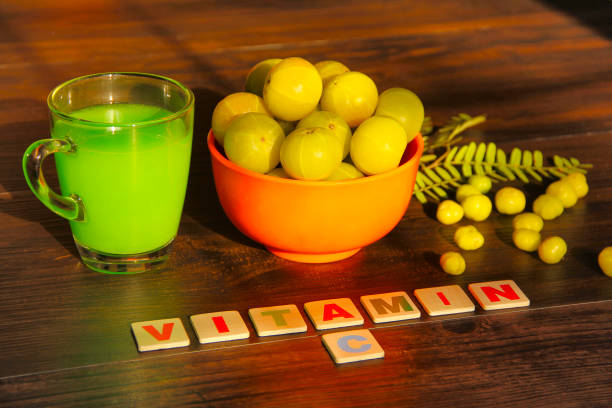 schale voll mit stachelbeeren, saft, blätter, sterne stachelbeeren und label vitamin c, isoliert auf braunem hintergrund - gooseberry fruit berry bowl stock-fotos und bilder