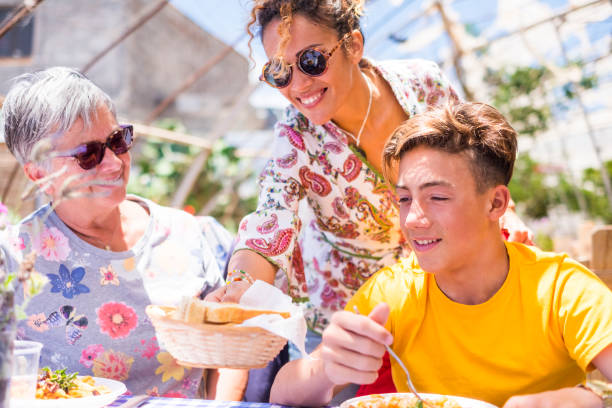 istock three family people with different ages and generations at lunch on a sunny day outdoor leisure activity, grandmother, mother and son heving fun together. people in happiness with smiles 968891586