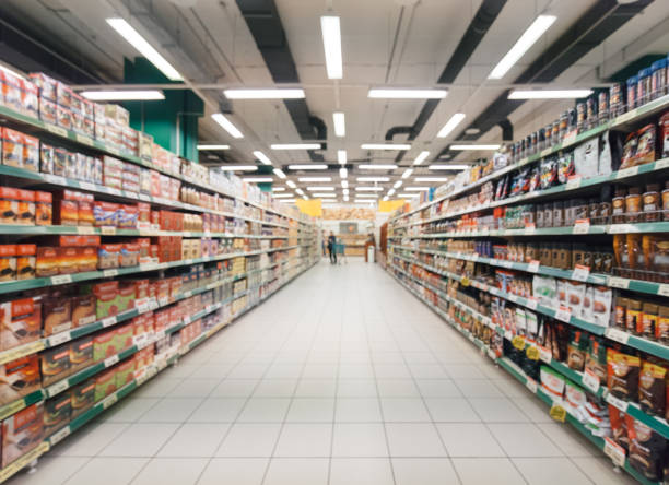 blurred supermarket aisle Abstract blurred supermarket aisle with colorful shelves and unrecognizable customers as background groceries stock pictures, royalty-free photos & images