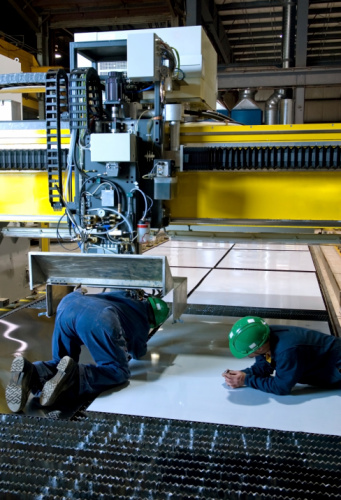 Workers change a head on a laser cutter used for metal work.