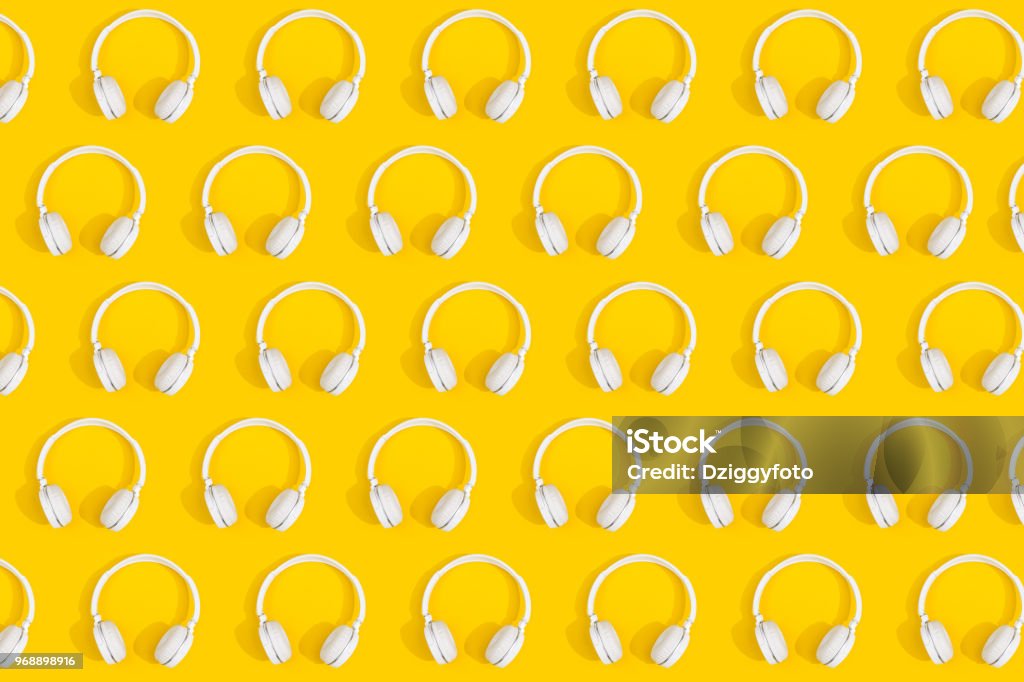 Headphones Repetitive pattern of white wireless headphones on yellow background Pattern Stock Photo