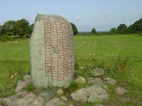 Close up low angle view of a large rune stone in Sweden. In summer sunlight and a blue sky