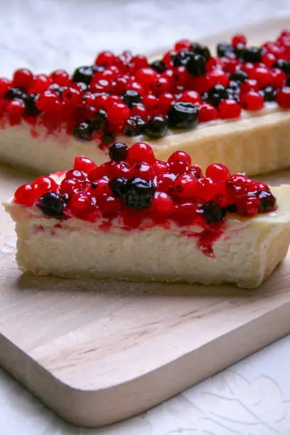 Cheesecake with redberries and blueberries on wooden board and sugar powder