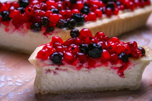 Cheesecake with redberries and blueberries on wooden board and sugar powder