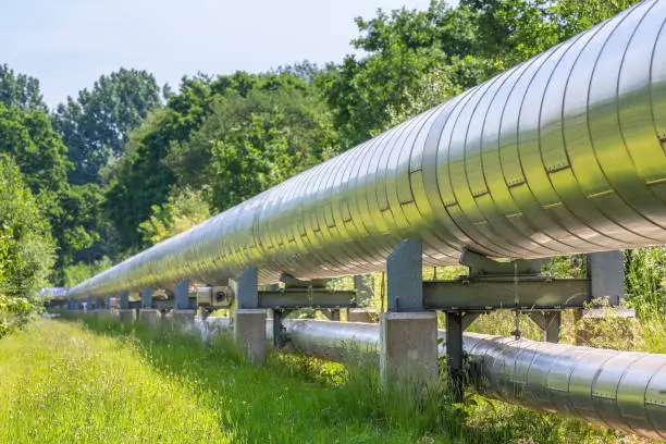 Huge metal gas pipeline distributing gas outside. In the Netherlands they extract gas as energy out of the ground. It is distributed above the ground through large and long gas pipelines like you see here. The dutch government is planning to stop the use of gas for the dutch households and also for the industry. Using electric energy will be better for our natural environment.