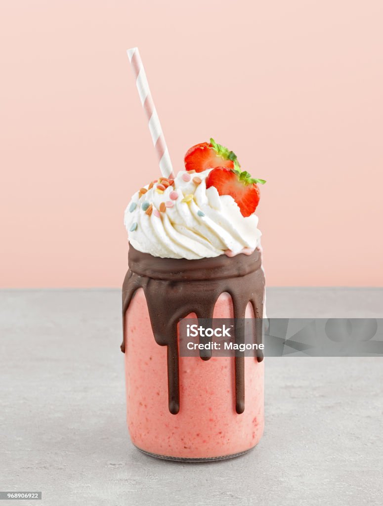 jar of strawberry and banana milkshake jar of strawberry and banana milkshake decorated with whipped cream and melted chocolate Milkshake Stock Photo