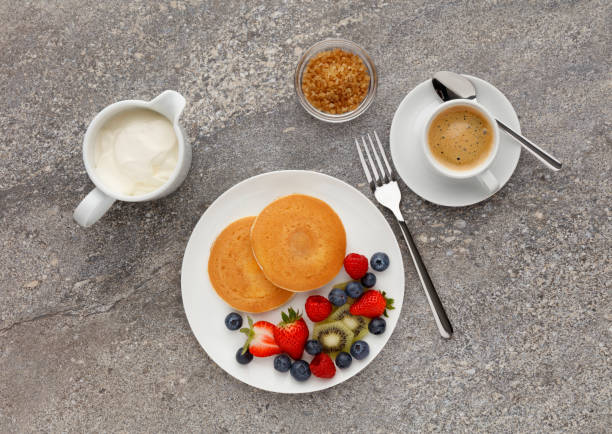 istock Continental breakfast of a Pancakes, fruit, and coffee, shot on a Stone kitchen work top 968907904