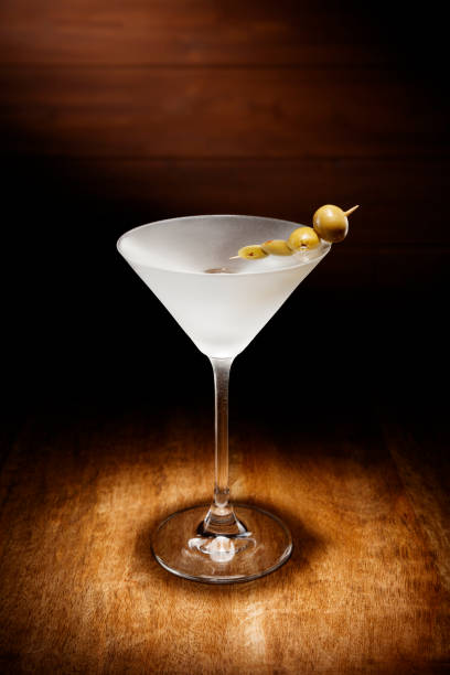 istock Spotlight on a single chilled martini, with olives, shot on a dark wooden background. 968908086
