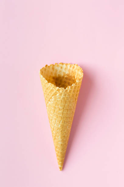 istock Flat-lay of waffle sweet cone over pastel light pink background, top view. 968910568