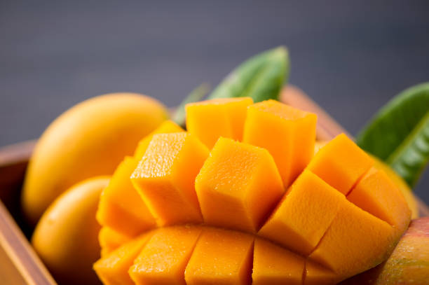 istock Fresh and beautiful mango fruit set in a wooden box with sliced diced mango chunks on a dark wooden background, copy space(text space), blank for text 968917018