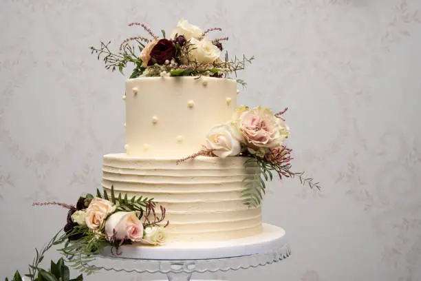 Champagne wedding cake with yellow and pink flower arrangements