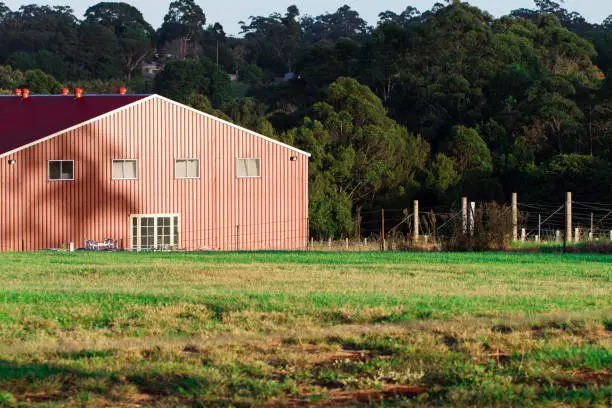 Photo of Red timber barn house in farm green grassy paddock