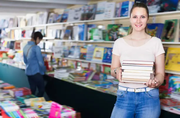 Laughing woman buying books in hard cover in bookstore