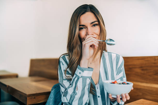 femme de près par manger bol d’avoine et fruits pour le petit déjeuner - fruit women beautiful food photos et images de collection