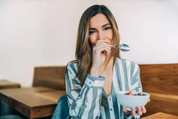 Photo of woman close up eating oat and fruits bowl for breakfast
