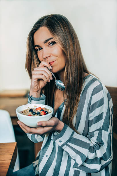 donna da vicino mangiare avena e frutta ciotola per la colazione - oatmeal porridge bowl spoon foto e immagini stock