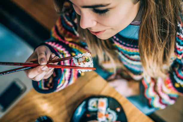 istock from above Crop woman eating sushi 968935238