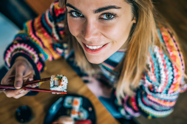Top view Crop woman eating sushi
