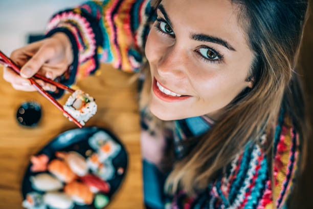 istock from above Crop woman eating sushi 968935264