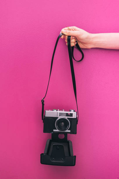 istock Hand holding a Vintage camera isolated at pink wall 968935364